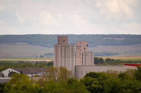 Foto de Reims, Francia - Mayo 2021 - Visto desde lejos, elevadores de granos por Pr des Moines Quay, en Champagne, una región que alberga un poderoso negocio agrícola; en el horizonte, la montaña montañosa y boscosa de Reims - Imagen libre de derechos