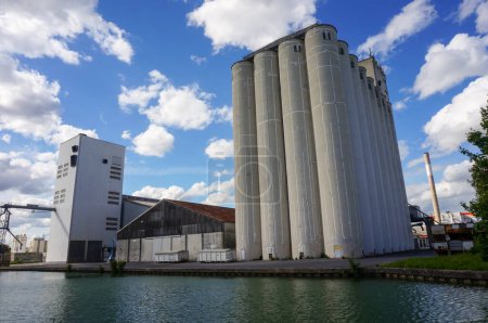Photo for Reims, France - May 2021 - Grain silos and industrial facilies at the river port of Pre des Moines Quay, by Marne-Aisne Canal, in the Champagne Region, which hosts a powerful agri-food industry - Royalty Free Image