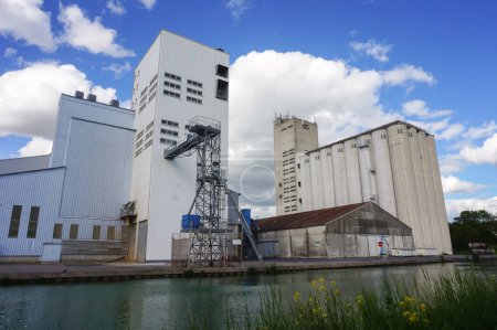 Foto de Reims, Francia - Mayo 2021 - Elevadores de granos y fábricas industriales en el puerto fluvial de Pre des Moines Quay, junto al canal Marne-Aisne, en la región de Champagne, que alberga un poderoso agronegocio - Imagen libre de derechos