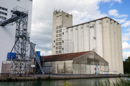 Foto de Reims, Francia - Mayo 2021 - Elevadores de granos y fábricas industriales en el puerto fluvial de Pre des Moines Quay, junto al canal Marne-Aisne, en la región de Champagne, que alberga un poderoso agronegocio - Imagen libre de derechos