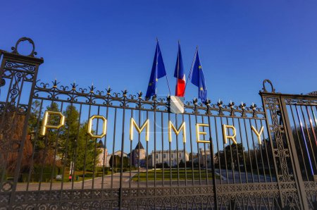 Foto de Reims, Francia - Marzo 2021 - Cartas doradas que dicen "Pommery", y banderas, en la puerta de hierro fundido que protege la finca vinícola y la sede histórica del productor francés de champán Vranken-Pommery - Imagen libre de derechos