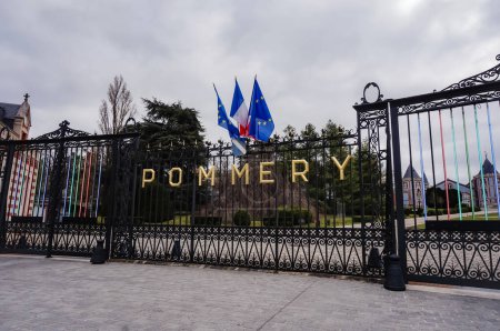 Foto de Reims, Francia - Abril 2021 - Cartas doradas que dicen "Pommery", y banderas, en la puerta de hierro fundido que protege la finca vinícola y la sede histórica del productor francés de champán Vranken-Pommery - Imagen libre de derechos