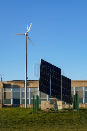 Photo for Reims, France - March 2021 - Photovoltaic panels and experimental wind turbine in front of the Renewable Energy Unit of the Department of Automation of Reims University, on Moulin de la Housse Campus - Royalty Free Image