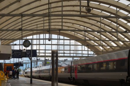 Foto de Reims, Francia - junio de 2021 - Los arcos abovedados de hormigón que sostienen el gran techo de cristal que cubre las vías de la estación de tren Reims Centre, y un tren operado por la SNCF en escala en la plataforma - Imagen libre de derechos