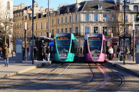 Foto de Reims, Francia - Feb. 2022 - Dos modernos trenes ligeros Alstom de color turquesa y rosa lado a lado, dirigidos por la empresa de transporte Citura, en la plataforma, frente a la estación de tren (Gare Centre) - Imagen libre de derechos