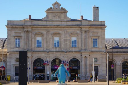 Foto de Reims, Francia - Marzo 2022 - Fachada del siglo XIX de la terminal de pasajeros de la estación ferroviaria Reims Centre, una infraestructura de transporte en el centro de la ciudad, con una estatua temporal en primera línea - Imagen libre de derechos