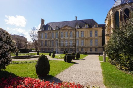 Photo for Reims, France - March 2021 - French-style garden and facade of the 17th century building of the "Palais du Tau" (Tau Palace), formerly an episcopal residence, whose chapel is visible on the right - Royalty Free Image
