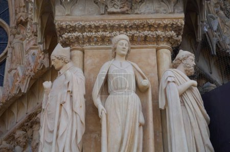 Foto de Estatua rica, esculpida del siglo XIII, de la catedral de Notre-Dame de Reims, en Francia, en el portal de entrada: aquí un grupo de tres estatuas, una mujer y dos hombres, incluyendo un Papa con su tiara - Imagen libre de derechos