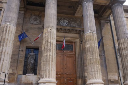 Foto de Reims, Francia - Marzo 2021 - Colonnade and wooden door at the entrance of the 19th century, No-Grec building of the Palace of Justice, where banderas de Francia y de la Unión Europea - Imagen libre de derechos