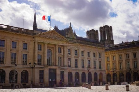 Foto de Reims, Francia - marzo de 2021 - fachada del edificio del siglo XVIII de la subprefectura del Marne, enarbolando una bandera francesa, en la Place Royale; en la parte posterior, la torre y las torres de la Catedral de Notre-Dame - Imagen libre de derechos