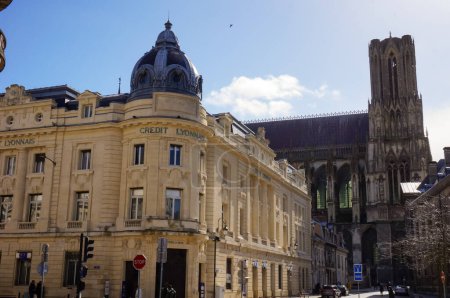 Foto de Reims, Francia - Marzo 2021 - Un edificio abovedado del siglo XX en la esquina de las calles de Cours Langlet, Rue Carnot y Rue du Tresor; a lo lejos, el campanario de la catedral gótica de Notre-Dame - Imagen libre de derechos