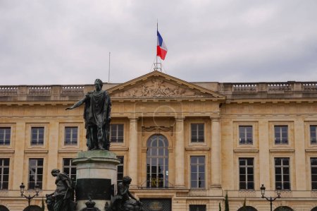 Photo for Reims, France - April 2021 - Bronze statue of French King Louis XV, in front of the classical building of the Sub-Prefecture, which is topped with a flag of France, on Place Royale (Royal Square) - Royalty Free Image