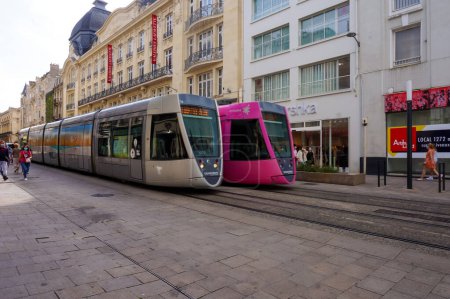 Foto de Reims, Francia - Junio 2021 - Dos modernos trenes de tranvía de Alstom se cruzan en la calle Rue de Vesle, frente al edificio Galeries Lafayette, en el centro histórico de la capital de Champagne - Imagen libre de derechos