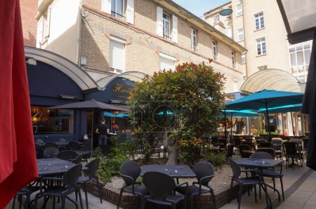 Foto de Reims, Francia - Junio 2022 - Una terraza restaurante en un patio interior, al final del Passage du Commerce, por Rue de Vesle, centro de la ciudad; la plaza está bordeada de edificios de apartamentos de ladrillo - Imagen libre de derechos