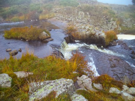 Photo for Exceptional geological site in Lozre, France : basaltic hexagonal prisms from an ancient lava flow eroded by the water of the river Les Plches, in Pont des Ngres, flowing by producing white foam - Royalty Free Image