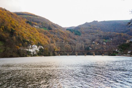 Téléchargez les photos : Vue pittoresque sur le Tarn, coulant au pied d'une colline colorée et boisée à Lincou, un emplacement rural dans l'Aveyron, sud de la France, avec une forêt aux tons automne et hiver - en image libre de droit
