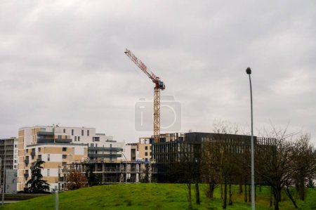 Téléchargez les photos : Toulouse, France -Déc. 2019- Cadre d'un nouveau gratte-ciel en construction avec une grue à tour entre autres immeubles d'appartements et de bureaux, dans un quartier résidentiel en pleine expansion de la banlieue de la ville - en image libre de droit
