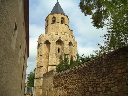 Foto de Campanario y últimos vestigios de la iglesia gótica medieval de Saint-Martin en el histórico pueblo de Sorze en el sur de Francia, con contrafuertes de piedra coronados por creneles y un techo de pizarra - Imagen libre de derechos