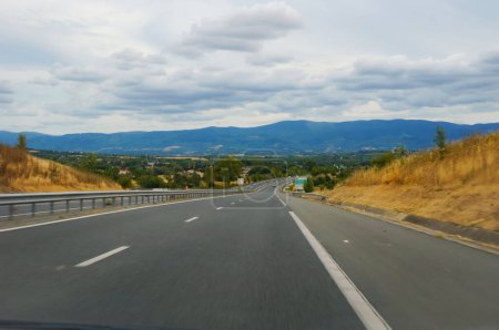 Téléchargez les photos : Le beau relief boisé de la Montagne Noire, une zone rurale paisible dont la capitale est Castres, dans le sud de la France, au loin à l'horizon, vue d'une partie en pente de l'autoroute D1012 - en image libre de droit