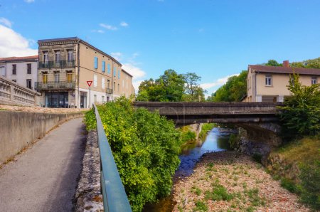 Téléchargez les photos : Un sentier en pente descend par la Durenque, un affluent de la rivière Agot, dont le lit est à moitié sec en été ; un petit pont voûté traverse ce ruisseau qui coule à Castres, dans le sud de la France - en image libre de droit