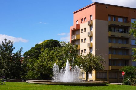 Foto de Chorros de agua en una fuente, en medio de una plaza verde por Boulevard Henri Sizaire, en el centro de la ciudad de Castres, en el suroeste de Francia; detrás de la plaza, un edificio de apartamentos de seis pisos - Imagen libre de derechos