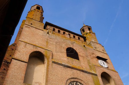 Foto de Vista en ángulo bajo del campanario y doble pináculo de la iglesia de Notre-Dame du Bourg, un gótico medieval del sur de la UNESCO Patrimonio de la Humanidad en Rabastens, Francia, con un reloj en la fachada frontal - Imagen libre de derechos