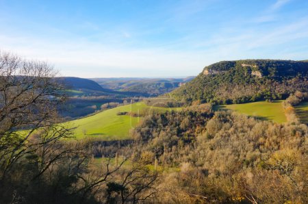 Foto de Hermoso paisaje verde de bosque y montaña en la zona rural de Puycelsi en el sur de Francia, con una meseta de piedra caliza boscosa con un afloramiento rocoso, campos en el valle y colinas a lo lejos - Imagen libre de derechos