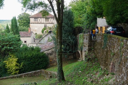Foto de Cordes-sur-Ciel, Francia - Agosto de 2021 - Murallas de piedra y casas antiguas y tradicionales en un entorno verde y frondoso, en el pueblo fortificado de Cordes-sur-Ciel, una ciudad medieval en el Tarn, cerca de Albi - Imagen libre de derechos