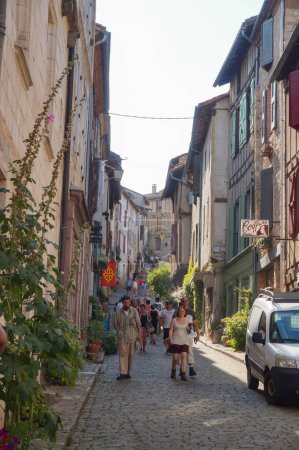 Foto de Cordes-sur-Ciel, Francia - Agosto de 2021 - Los turistas que visitan el pueblo medieval en la "Rue de la Bouteillerie", una calle inclinada llena de tiendas tradicionales y edificios típicos de piedra antigua ciudad - Imagen libre de derechos