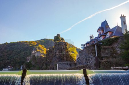 Foto de El agua verde del río Tarn que fluye sobre la presa de la isla de Ambialet, un pintoresco pueblo en el sur de Francia, con una antigua iglesia medieval construida sobre un acantilado rocoso en el fondo - Imagen libre de derechos