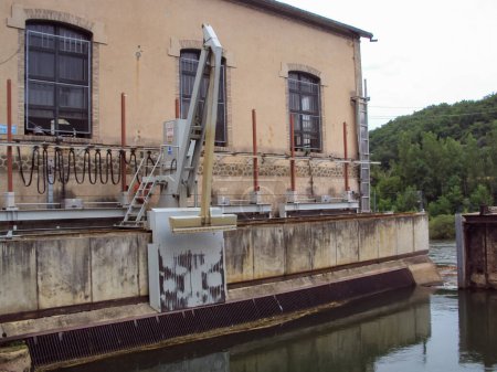 Foto de Les Avalats, Francia - Circa 2016 - Trash Rack Cleaning Machine (TRCM) y las instalaciones industriales de una presa hidroeléctrica EDF, equipada con un brazo telescópico e instalada por el agua del río Tarn - Imagen libre de derechos