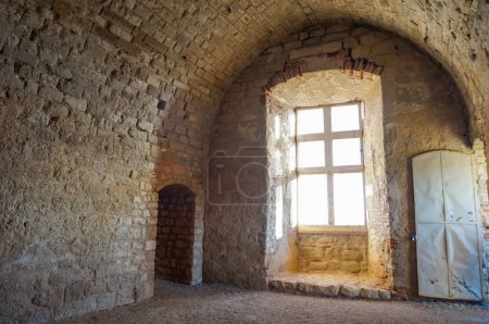 Foto de Dentro de las ruinas del castillo de Castelnau-de-Lvis, al sur de Francia: ventanal medieval en la sala principal abovedada de la casa señorial - Imagen libre de derechos