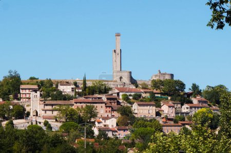 Foto de Hermosa vista desde el río Tarn en Castelnau-de-Lvis, un pueblo fortificado en Occitanie, Francia, dominado por la torre de vigilancia de un castillo medieval en ruinas construido en la cima de una colina boscosa verde - Imagen libre de derechos