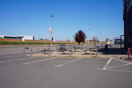 Téléchargez les photos : Albi-Le Sequestre, France - Avril 2020 - Pas de voiture dans un parking vide et des tables désertes d'un restaurant fermé dans le centre commercial de La Baute, au milieu des mesures de confinement du coronavirus - en image libre de droit