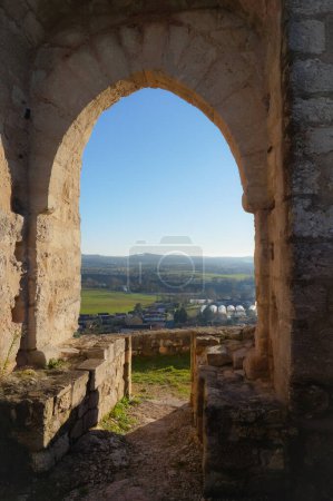 Téléchargez les photos : Au loin, vue sur la plaine verdoyante et les collines d'Albi, à travers les vestiges d'une porte fortifiée voûtée dans le château médiéval de Castelnau-de-Levis, en France, un ancien bastion construit en calcaire - en image libre de droit