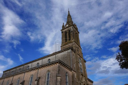 Photo for The front of the neogothic church of Villefranche d'Albigeois, a village in the South of France ; the religious building features a rosette, stained glass windows and a bell tower topped by a cross - Royalty Free Image
