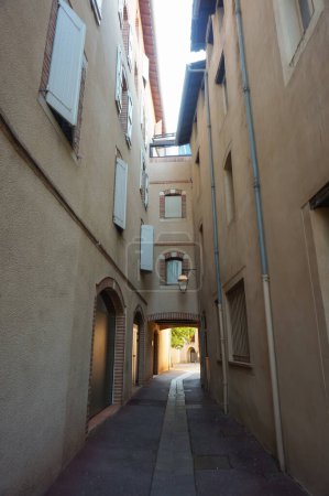 Foto de Albi, Francia - agosto de 2021 - La antigua y estrecha calle de Rue Trencavel, bordeada de casas tradicionales que están conectadas entre sí, de un lado a otro, con un puente que domina la calle - Imagen libre de derechos