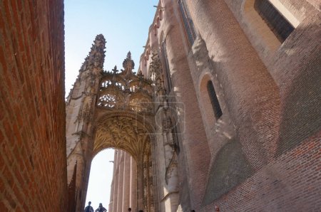 Foto de Albi, Francia - agosto de 2021 - Vista de bajo ángulo de la tardía Porte Dominique de Florence medieval, una llamativa puerta arqueada gótica, en la catedral de Sainte-Cecile, construida en ladrillo, Patrimonio de la Humanidad por la UNESCO - Imagen libre de derechos