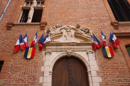 Téléchargez les photos : Albi, France - Août 2020 - Une vieille porte en bois avec un cadre en pierre sculptée orné de drapeaux français et de blasons de la République, à l'hôtel de ville, qui est logé dans un manoir du 17ème siècle sud - en image libre de droit