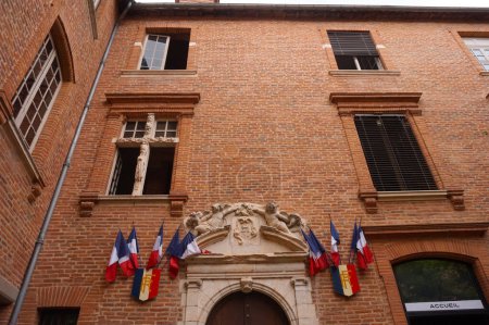 Téléchargez les photos : Albi, France - Août 2020 - Façade en brique de l'hôtel de ville, logée dans un "htel particulier" de style sud du XVIIe siècle, avec un porche en pierre orné de drapeaux français - en image libre de droit