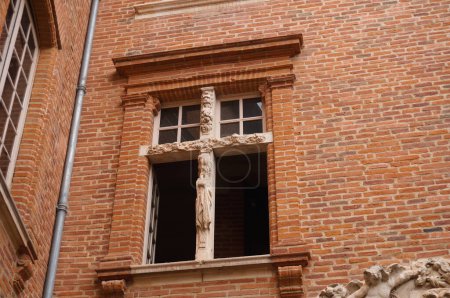 Photo for Albi, France - Aug. 2020 - Detail of an old, cross window, with a sculpted stone and brick frame, of the Southern-style "htel particulier", a 18th century townhouse, that houses the city hall - Royalty Free Image