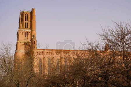 Photo for Side view of the Southern gothic Cathedral of Sainte-Cecile in Albi, France, partly hidden behind trees, in 2021 ; this medieval UNESCO World Heritage Site is the largest brick building globally - Royalty Free Image