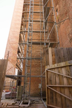 Photo for Bottom view of scaffolding set up against an old, medieval brick tower in the UNESCO World Heritage Area of the Old City of Albi, in the South of France, to perform restoration works at height - Royalty Free Image