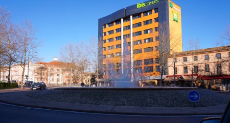 Téléchargez les photos : Albi, France - Déc. 2019 - Bâtiment moderne à plusieurs étages abritant un hôtel de style Ibis (anciennement Tour Groupama), surplombant la fontaine du rond-point de la place Jean Jaurs, dans le centre-ville - en image libre de droit