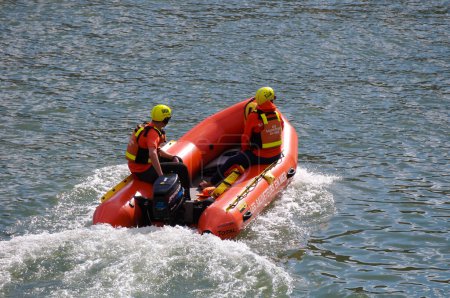 Foto de Toulouse, Francia - 2 de julio de 2023 - Dos salvadores del SNSM, vestidos con chalecos salvavidas y cascos naranjas y reflectantes, navegando por el río Garona en un bote infatigable, junto al Puerto de la Daurade - Imagen libre de derechos