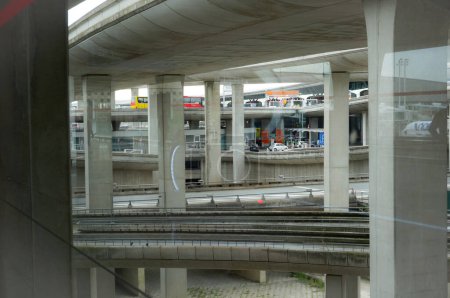 Foto de Aeropuerto París-Roissy Charles de Gaulle, Francia - Julio 2019 - Infraestructuras futuristas en el área de los aparcamientos: puentes superpuestos con cubiertas de hormigón visible y pilares en un diseño complejo - Imagen libre de derechos