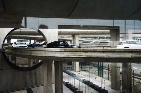 Téléchargez les photos : Aéroport Paris-Roissy Charles de Gaulle - Juillet 2019 - Infrastructures futuristes : voitures sur des ponts superposés traversant un oculus près du dépôt, avec des tabliers et des piliers en béton visibles - en image libre de droit