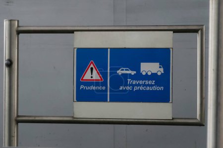 Photo for French-written warning sign (triangle with exclamation mark) on a tollgate barrier and traffic signal, showing the symbols of a car behind a truck : "Caution", "Cross (the road) with caution" - Royalty Free Image