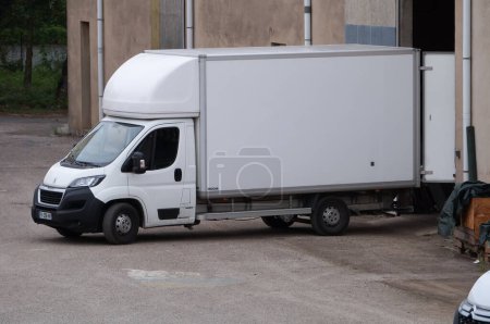 Téléchargez les photos : Albi, France - Juillet 2022 - Un camion Peugeot blanc à cube mobile à l'envers, en position de déchargement, les portes ouvertes, devant la porte coulissante d'un centre de stockage servant de dépôt de meubles - en image libre de droit