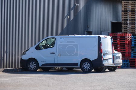 Téléchargez les photos : Albi, France - Juillet 2022 - Vue latérale d'une camionnette Renault Trafic blanche, garée à côté d'une pile de palettes en bois, devant un entrepôt, à l'arrière d'un hypermarché moderne E. Leclerc - en image libre de droit